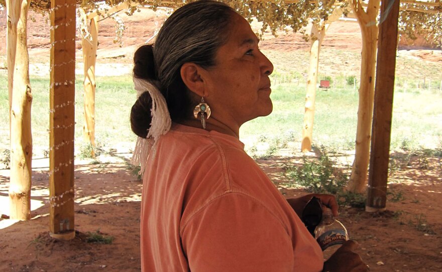 Lupita McClanahan, wearing a traditional Navajo hair knot tied with white yarn, in a shelter her husband built.