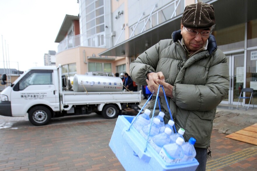 A man carries bottles of water after visiting a water tank in Urayasu, Chiba prefecture, near Tokyo. A spike in radiation levels in Tokyo tap water spurred new fears about food safety as rising black smoke forced another evacuation of workers trying to stabilize Japan's radiation-leaking nuclear plant.