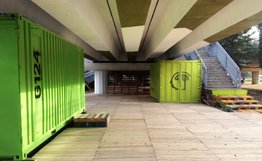A team of architects has cleaned up the garbage below the tracks and — using shipping containers and other recycled containers — have transformed a planned tram stop into a community space.