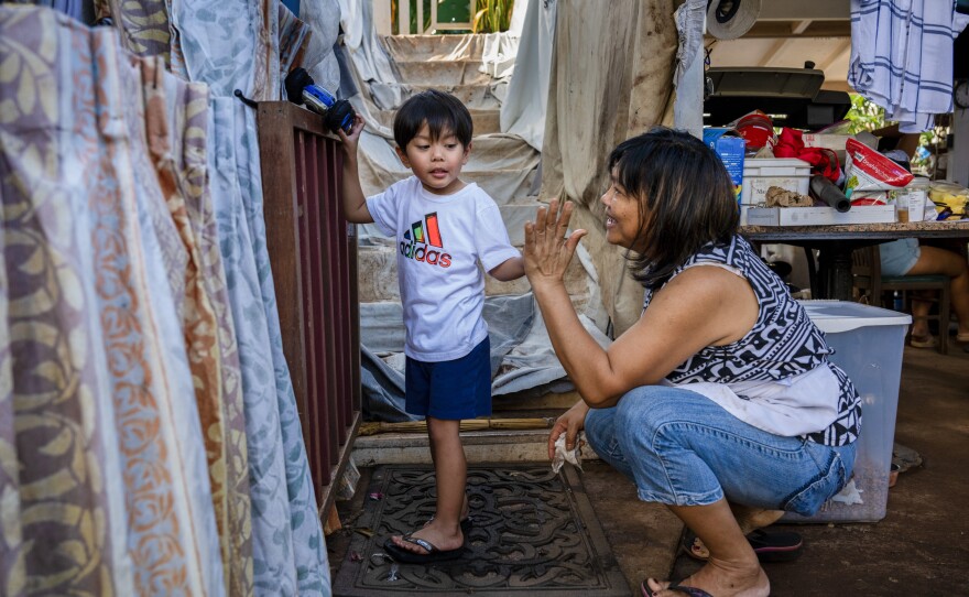 Emelyn Andres plays with her grandson Sebastian. She came to clean and pull ash-soiled contents out of her house, and haul it to the landfill. "I don't know how to begin to clean," Emelyn says.