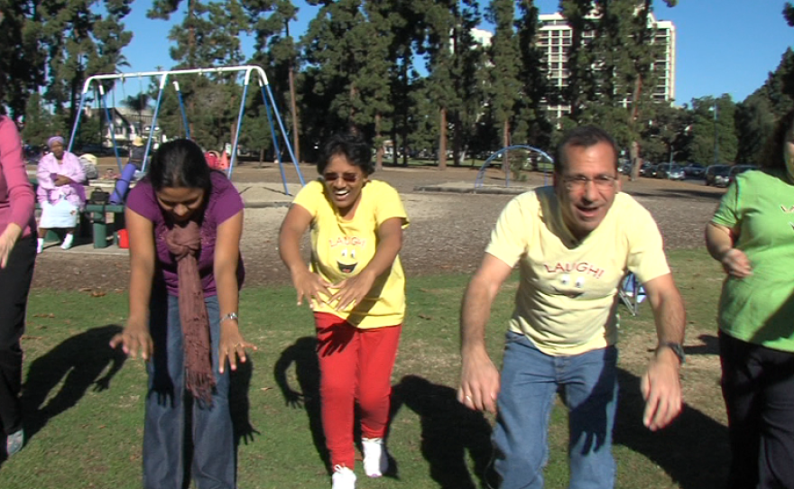 Michael Coleman, the director of Laughter Matters, and other laughter yoga participants play in Balboa Park.