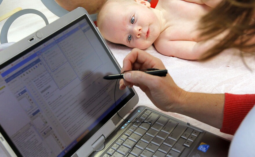Patient William Wishart, age 4 months, looks on as Dr. Melanie Walker uses a portable computer to enter information from his exam into an electronic medical records system, in North Raleigh, N.C., in November.