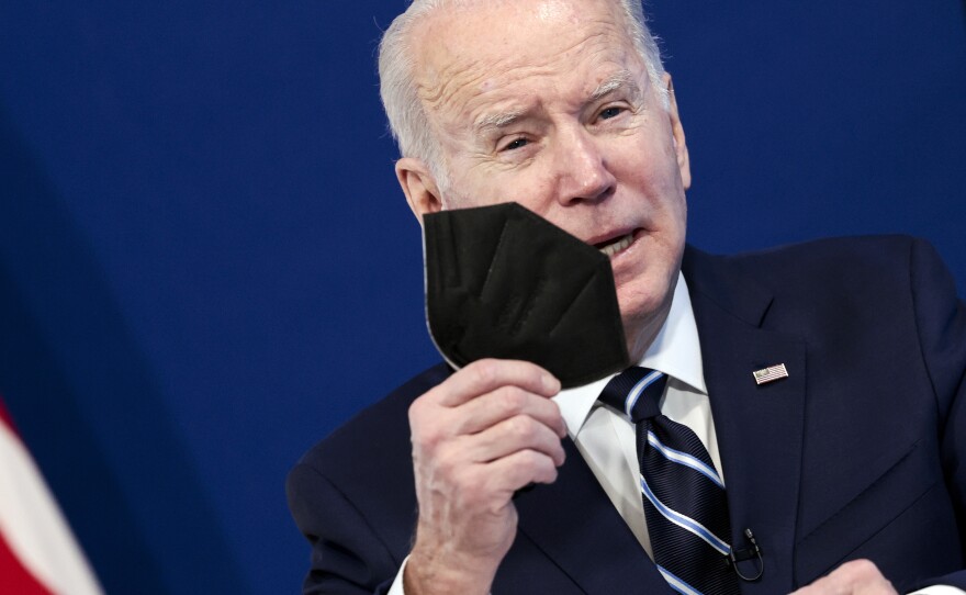 Joe Biden holds a mask as he gives remarks on his administration's response to the surge in COVID-19 cases across on January 13, 2022.