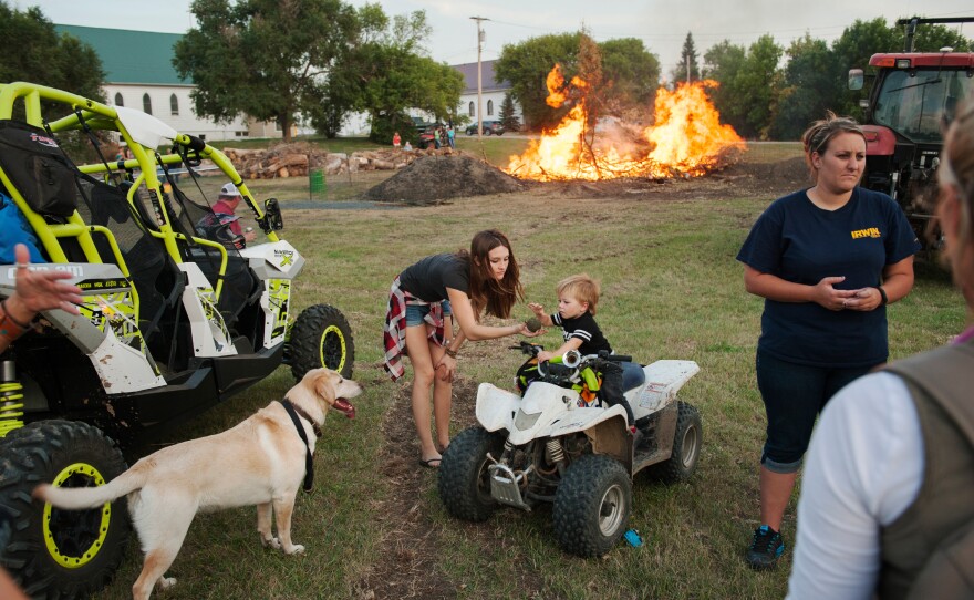 Bailey Morris and her nephew Tucker Lynn play with a dog at a bonfire during Old Settlers Days in Alexander in September. The coals of the bonfire are used to cook about 1,000 pounds of meat to feed celebrants during the annual festival.