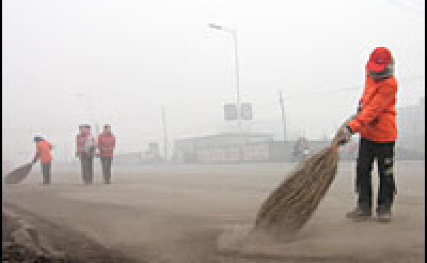 Street sweepers on the outskirts of Linfen face a losing battle while corralling coal dust into heaps as trucks hurtle past.
