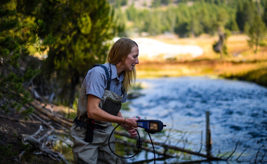 National Park Service hydrologist Erin White prepares to test the waters of the Firehole River near Yellowstone’s famous Old Faithful geyser.