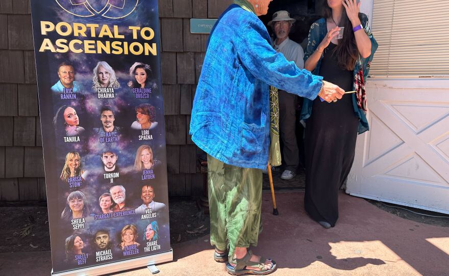 Two conference participants, one holding incense, are shown chatting together at Marina Village in San Diego on April 21, 2023.