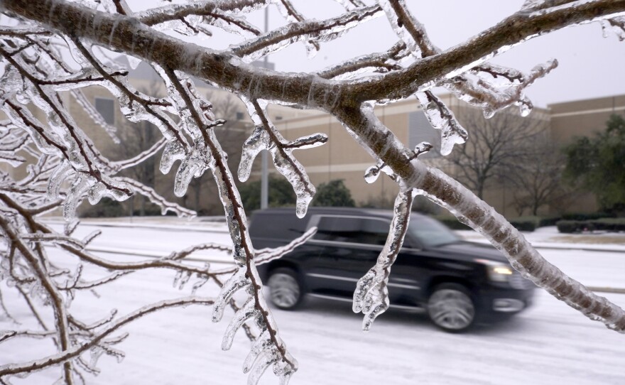 Ice coats trees and the road as an SUV drives in Richardson, Texas, on Thursday. A major winter storm with millions of Americans in its path is spreading rain, freezing rain and heavy snow further across the country.