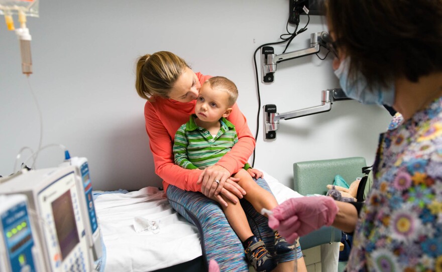 Luke Whitbeck, 2, sits on his mother's lap while the nurse prepares his treatment at a pediatric infusion center in Hawthorne, N.Y., in October 2016.