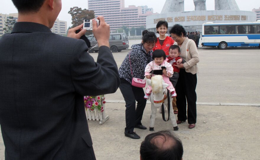 A family poses in front of the monument to the Foundation of the Workers' Party in Pyongyang, North Korea. Despite sanctions, the elite still have money to buy consumer products like digital cameras and mobile phones.