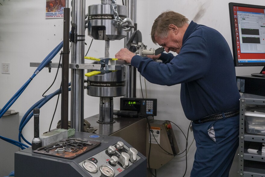 Craig Brooks, the president of AP/ES Inc., demonstrates a hydraulic press. Brooks' company, which develops ways to determine how long aircraft fleets will last, has won several Department of Defense contracts since the late 1990s.