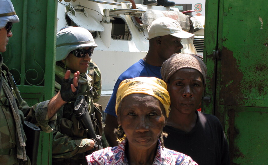 Women in Port-au-Prince wait for tarps and water jugs being handed out by the International Organization for Migration. U.N. troops provide essential security for such aid distribution efforts.