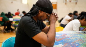 A person prays before receiving a free boxed lunch at City Life Center in Gary, Ind., Thursday, Aug. 20, 2026, more than a week after a deadly storm passed through the area.