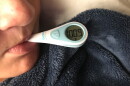 A boy with the flu takes his temperature at his home in San Diego, Feb. 14, 2018.
