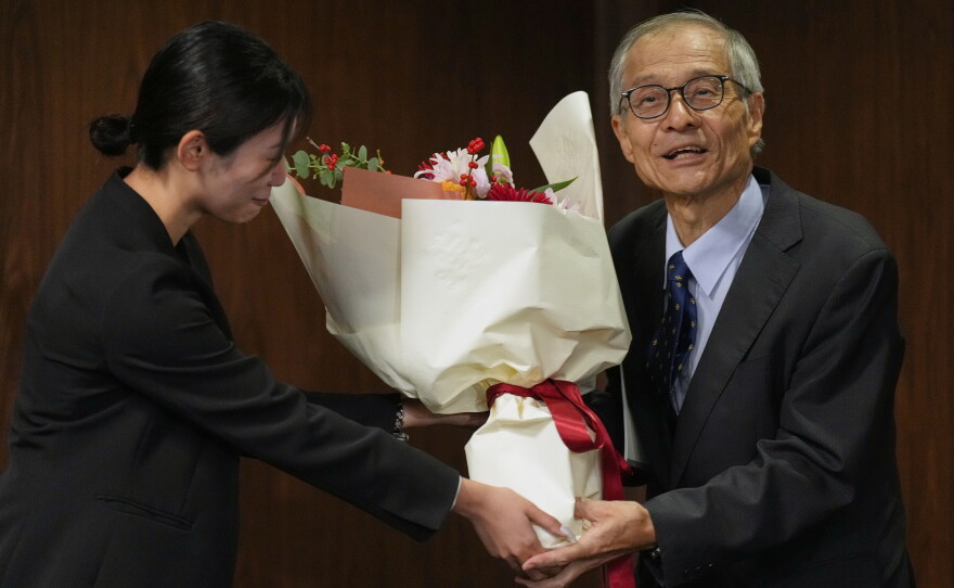 Japanese chemist Kenso Soai receives a bouquet of flowers from a university staff member before the press conference at Tokyo University of Science in Tokyo, Wednesday, Oct. 7, 2026, after winning the Nobel Prize in chemistry.