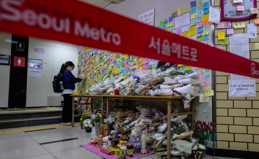 A woman pays her respects as she displays a note near the entrance to a female lavatory at Sindang station in Seoul on Sept. 19, 2022. Seoul Metro employee Jeon Joo-hwan was sentenced Tuesday for stabbing his colleague to death in the metro station's women's public toilet the day before a court was set to sentence him on charges of stalking her.