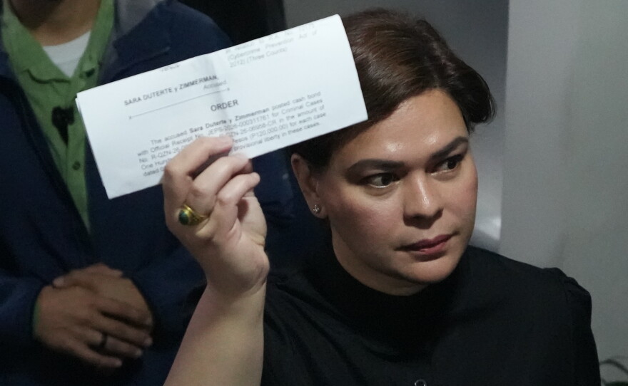 Philippine Vice President Sara Duterte shows a document to reporters at the Quezon city justice hall Saturday, Sept. 5, 2026, after an arrest warrant was issued on charges that she publicly threatened to have the president and two other people assassinated.
