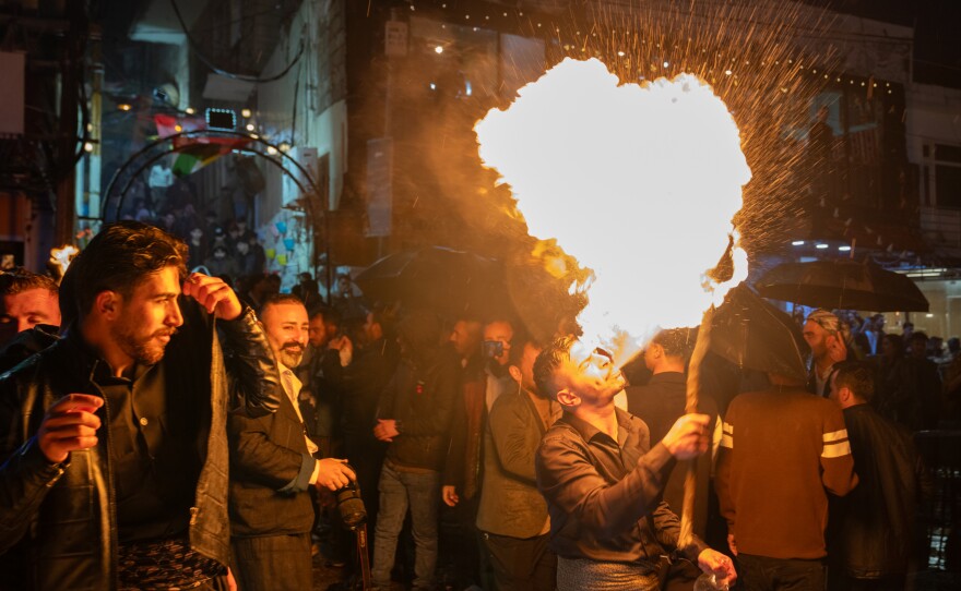 People walk through the center of Akre with flaming torches for Nowruz.