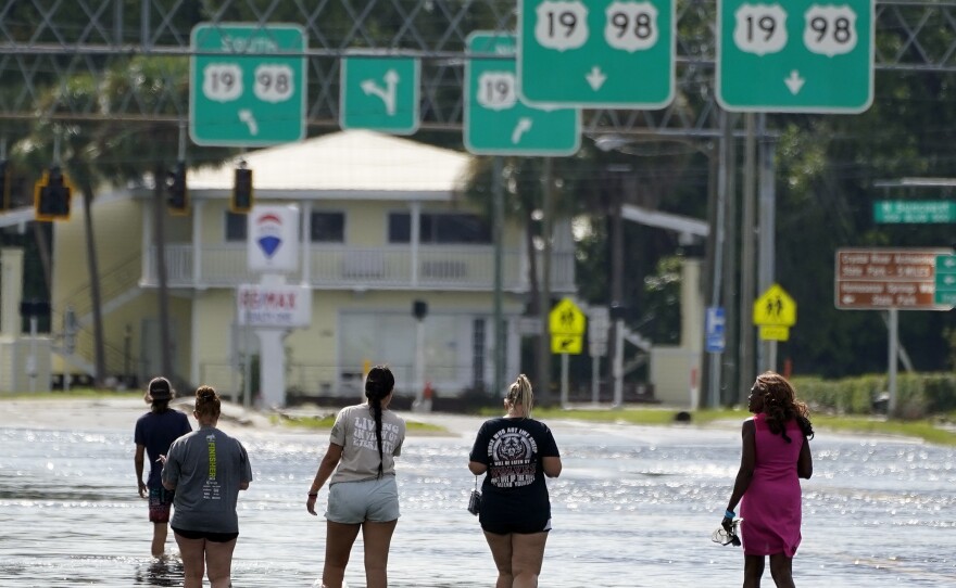 People walk through flood waters last month in Crystal River, Fla. Hurricane Idalia made landfall along the Big Bend region of Florida.