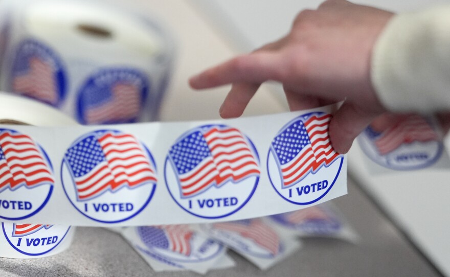 An election worker tears off "I Voted" stickers during the Virginia redistricting referendum at Fairfax Government Center, Tuesday, April 21, 2026, in Fairfax, Va.