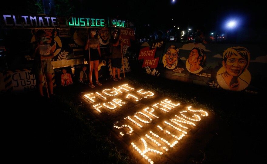 Climate activists in Quezon City, Philippines, light candles and hold LED-illuminated banners in December of last year to commemorates five years since the Paris Agreement and to call for an end to the killing of environmental defenders.