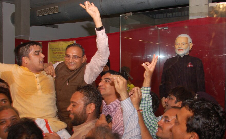 Diamond merchant Lalji Patel, center, celebrates Friday after he made the winning bid of more than 43 million rupees (about $695,000) for Indian Prime Minister Narendra Modi's dark suit with its unique monogram pinstripes.