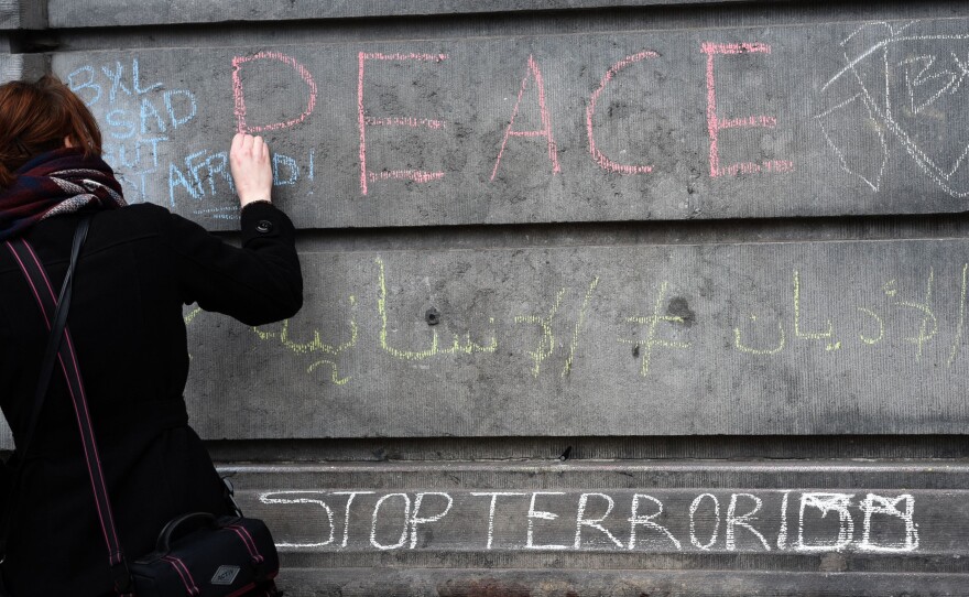 A woman writes a message on a wall in tribute to victims in Brussels on Wednesday, a day after deadly explosions struck the Belgian capital.