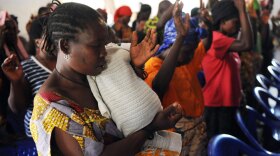 A Congolese rape victim joins others in raising their hands as they pray at a chapel inside the Heal Africa clinic in Goma, the epicenter of war-torn eastern Congo.