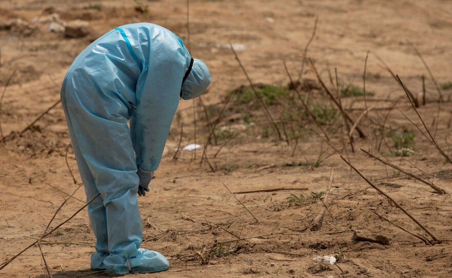 A health worker reacts on April 29, 2020, before the burial in New Delhi of a police officer who died of complications related to COVID-19.