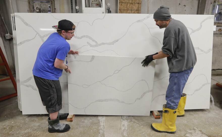 Workers move imported quartz slabs from China in the warehouse at Marble Uniques in Tipton, Ind., in 2019.