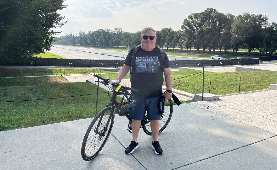 Joe Flood poses with his camera and bike near the reflecting pool on Monday. The D.C.-based photographer has been posting near-daily updates on social media since the renovations began.