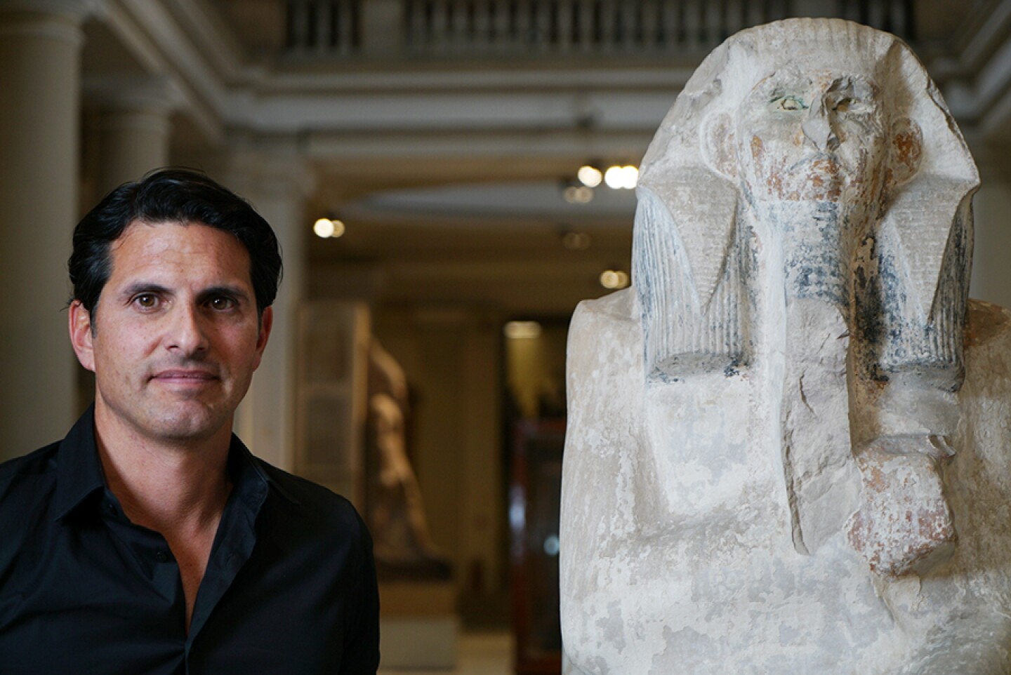 Presenter Darius Arya with a statue of King DJoser, who was buried in the Step Pyramid at Saqqara.