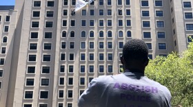 A protester watches a banner unfurl from the roof of the Westin San Diego in downtown, July 2, 2018.