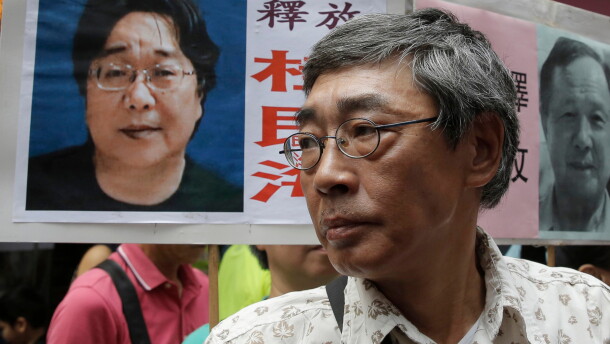 FILE - Freed Hong Kong bookseller Lam Wing-kee stands next to a placard with a picture of missing bookseller Gui Minhai, left, in front of his book store during a march in Hong Kong on June 18, 2016.