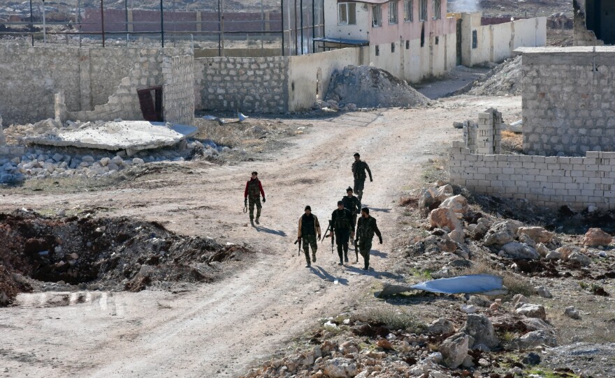 Syrian pro-government forces walk past damaged houses in eastern Aleppo, near Masaken Hanano, on November 23.