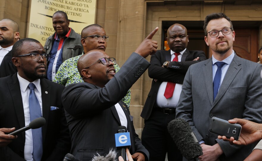 Nelson Mandela Foundation CEO Sello Hatang points to South Africa's current flag as he welcomes a ruling against its old flag in Johannesburg Wednesday. At right is Ernst Roets, leader of the AfriForum group that was targeted in the foundation's lawsuit.