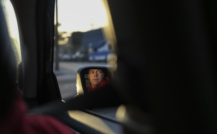 Ron Gochez, a teacher volunteering with Union del Barrio, an organization advocating for immigrant rights, is reflected in a side mirror as he searches for ICE activity in a neighborhood in Los Angeles Thursday, Feb. 27, 2025.