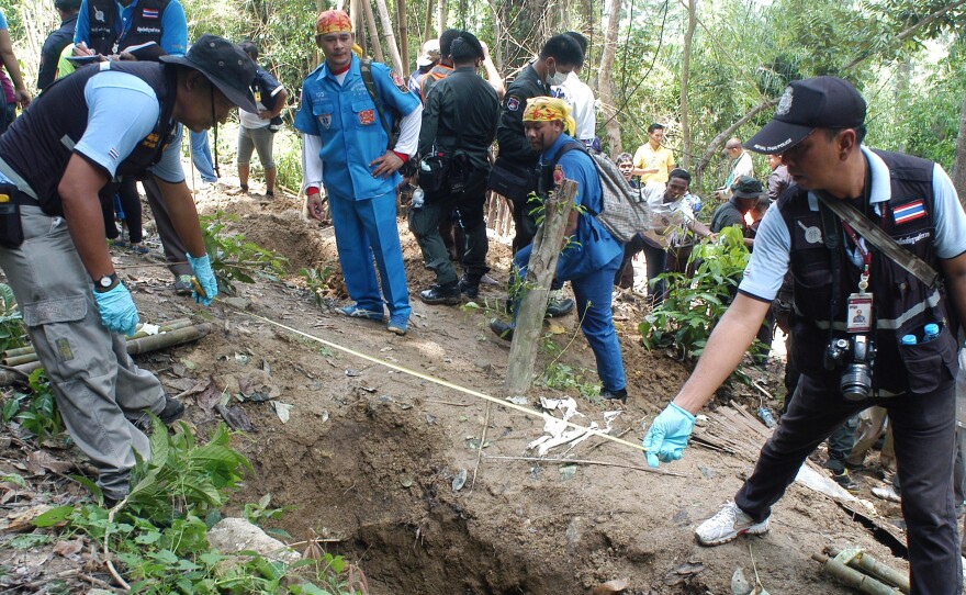 Thai policemen measure shallow graves in Songkhla province in southern Thailand on Saturday. Authorities say the 30 or so gravesites appear to contain remains of illegal migrants from neighboring Myanmar.
