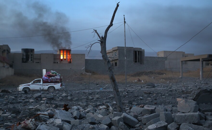 People remove household goods from the rubble as a house burns on Sunday in Sinjar, Iraq. Kurdish forces, with the aid of months of U.S.-led coalition airstrikes, liberated the town from ISIS.