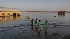 School children walk through the shallows past submerged and abandoned school buildings at the El Molo Bay primary school in Komote, Kenya. Teachers at the school say the buildings have become a breeding ground for crocodiles.