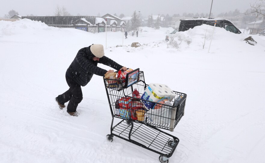A customer pushes their grocery cart through the snow to their car as a blizzard hits Mammoth Lakes, California, on Saturday.