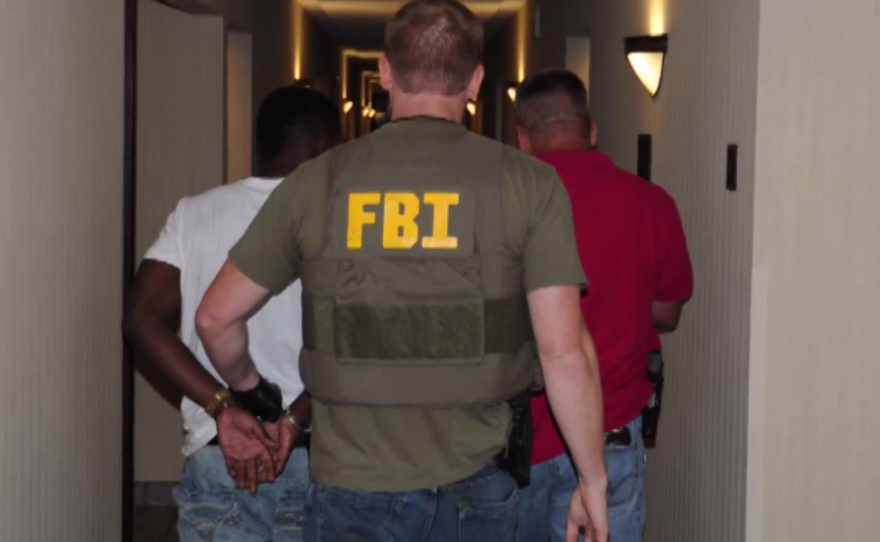 FBI agents walk with a man arrested as part of a nationwide crackdown on sex trafficking in this undated photo.