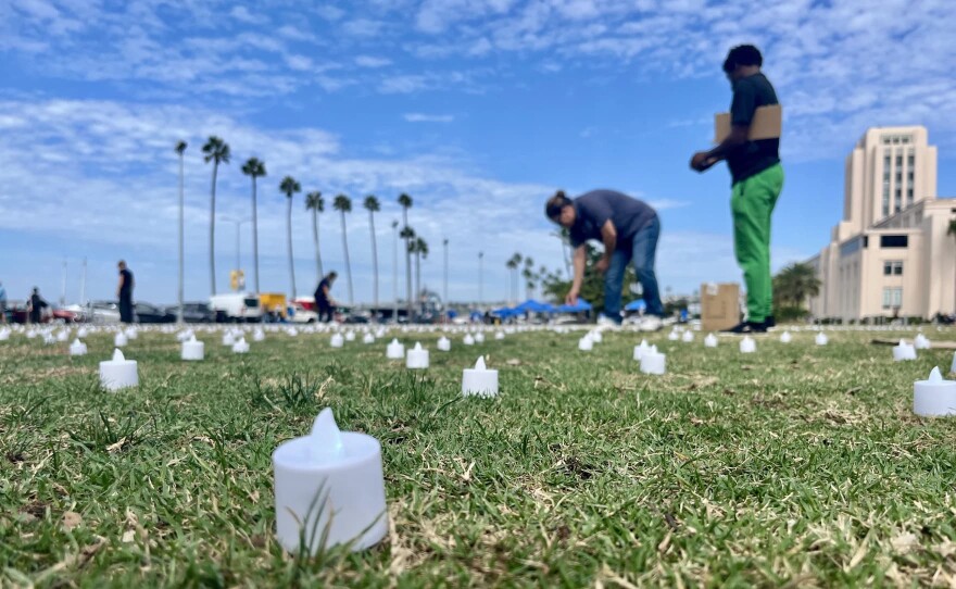 People set up flameless tea lights in San Diego's Waterfront Park on Oct. 10, 2025, preparing for a vigil to honor homeless San Diegans who have died.