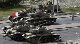 Bahraini army tanks take position near Pearl Square in Manama on Thursday after anti-riot police stormed through the square.