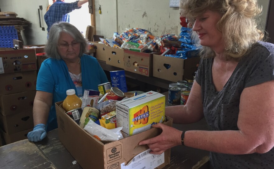 Cathy Rose is getting a box of free food from volunteer Rilda White at the pantry in Clintwood, Va. Rose says she relies on the free food because she lives on Social Security disability and the monthly check doesn't cover her bills.