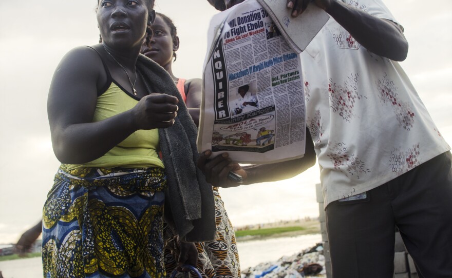 Residents of West Point read newspaper articles about the Ebola-related unrest in their community.