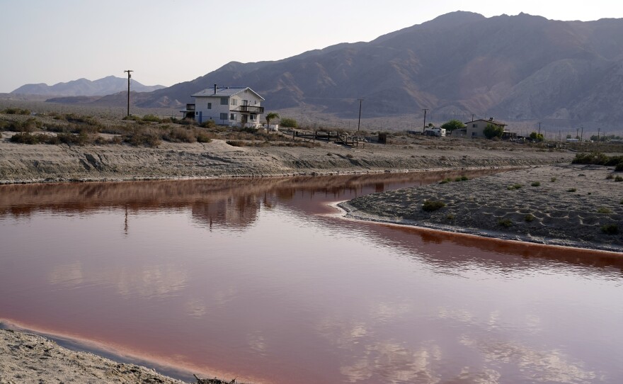 Clouds and nearby mountains are reflected in a polluted canal, once used as a boating dock, along the Salton Sea in Desert Shores, Calif., Wednesday, July 14, 2021.