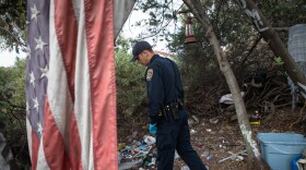 California Highway Patrol Officer Jesse Matias looks through an encampment near a freeway in San Diego, April 28, 2022. 