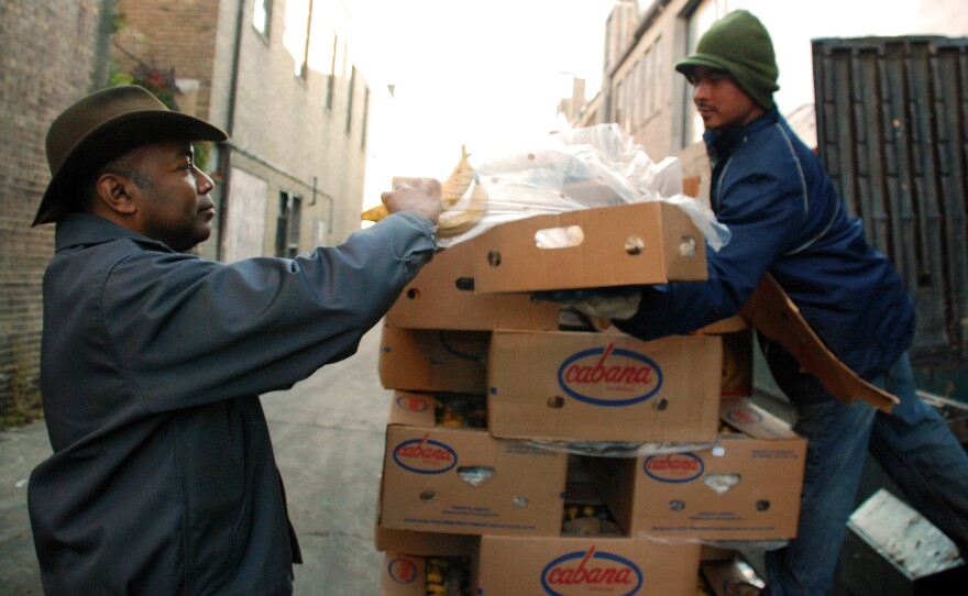 Roger Gordon (left) is offered a box of bananas from a worker who was throwing away the lightly speckled fruit at Mexican Fruits in Washington, D.C. Gordon's startup, Food Cowboy, works with truckers to divert edible produce from landfills to food charities.