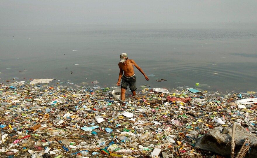 A fisherman collects water on a beach littered with trash at an ecological reserve south of Manila in 2013.